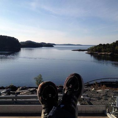 En ansatt som slapper av i en pause med elektriker arbeid med en fjord som utsikt 