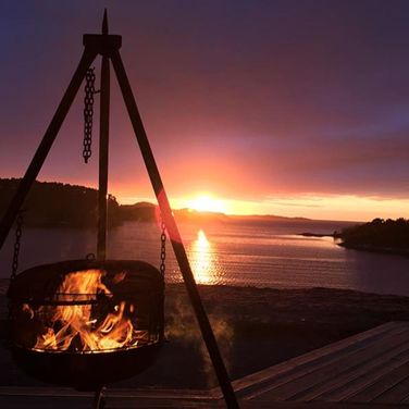 gryte som står over et bål med solnedgang i bakgrunnen